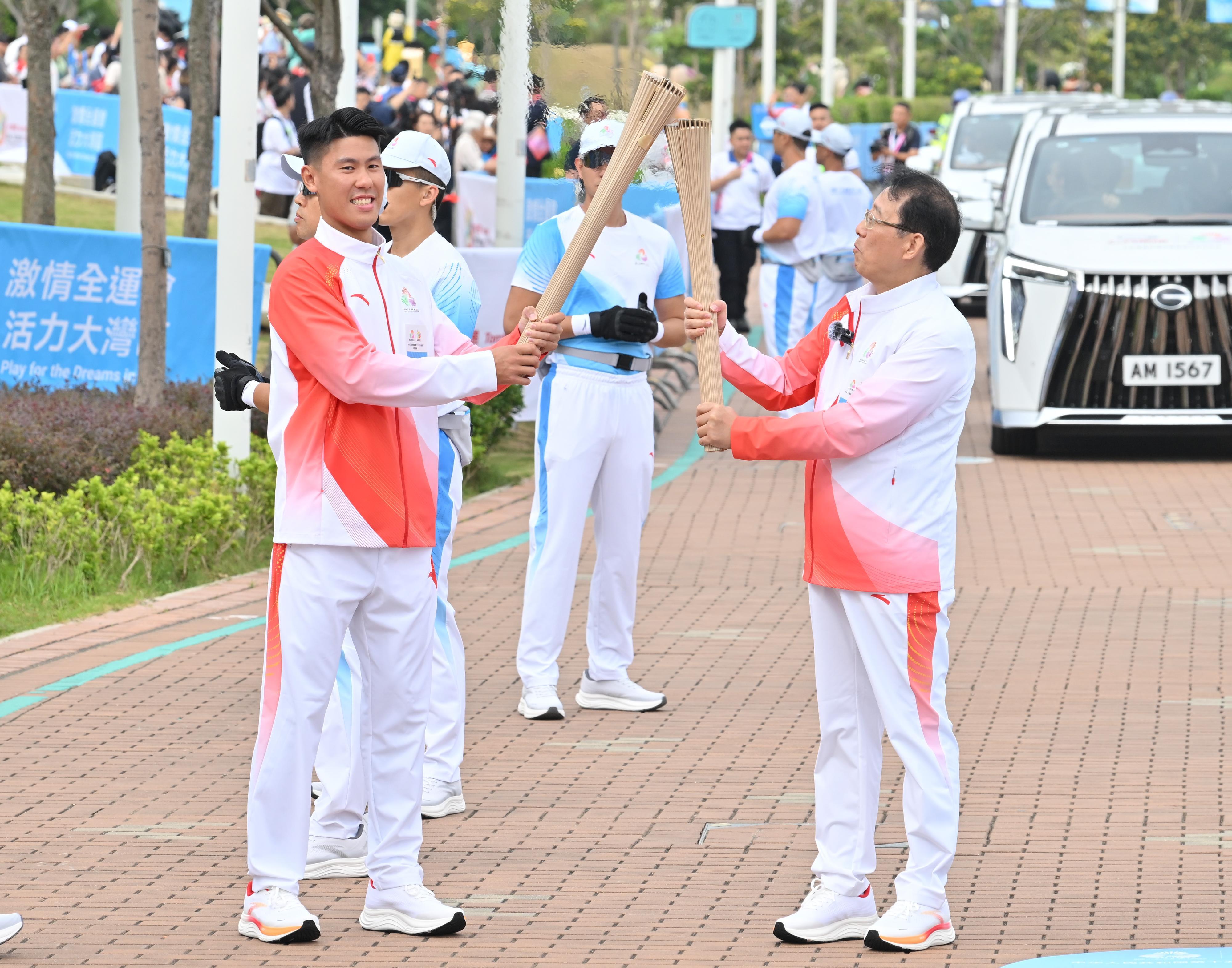 馮興亞（右）把火種傳給謝鍵泓（左）。