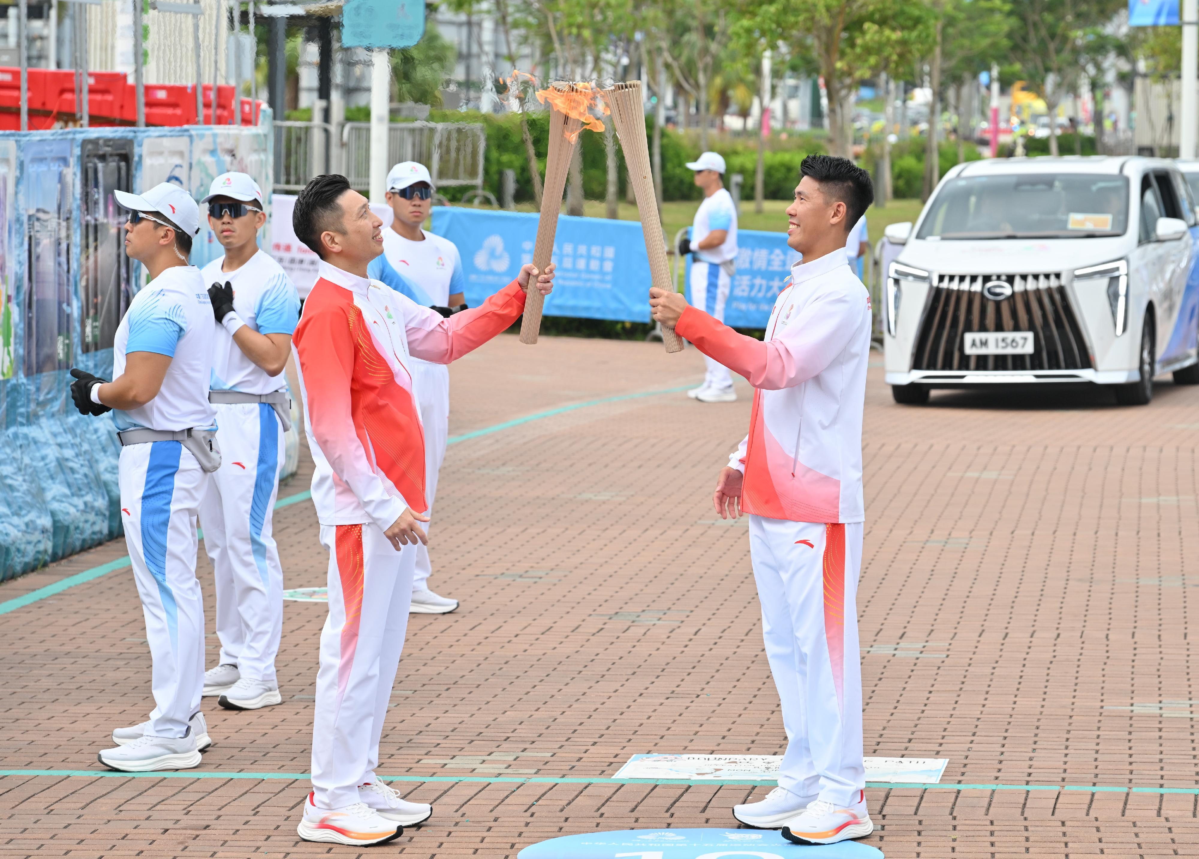 謝鍵泓（右）把火種傳給朱加勤（左）。