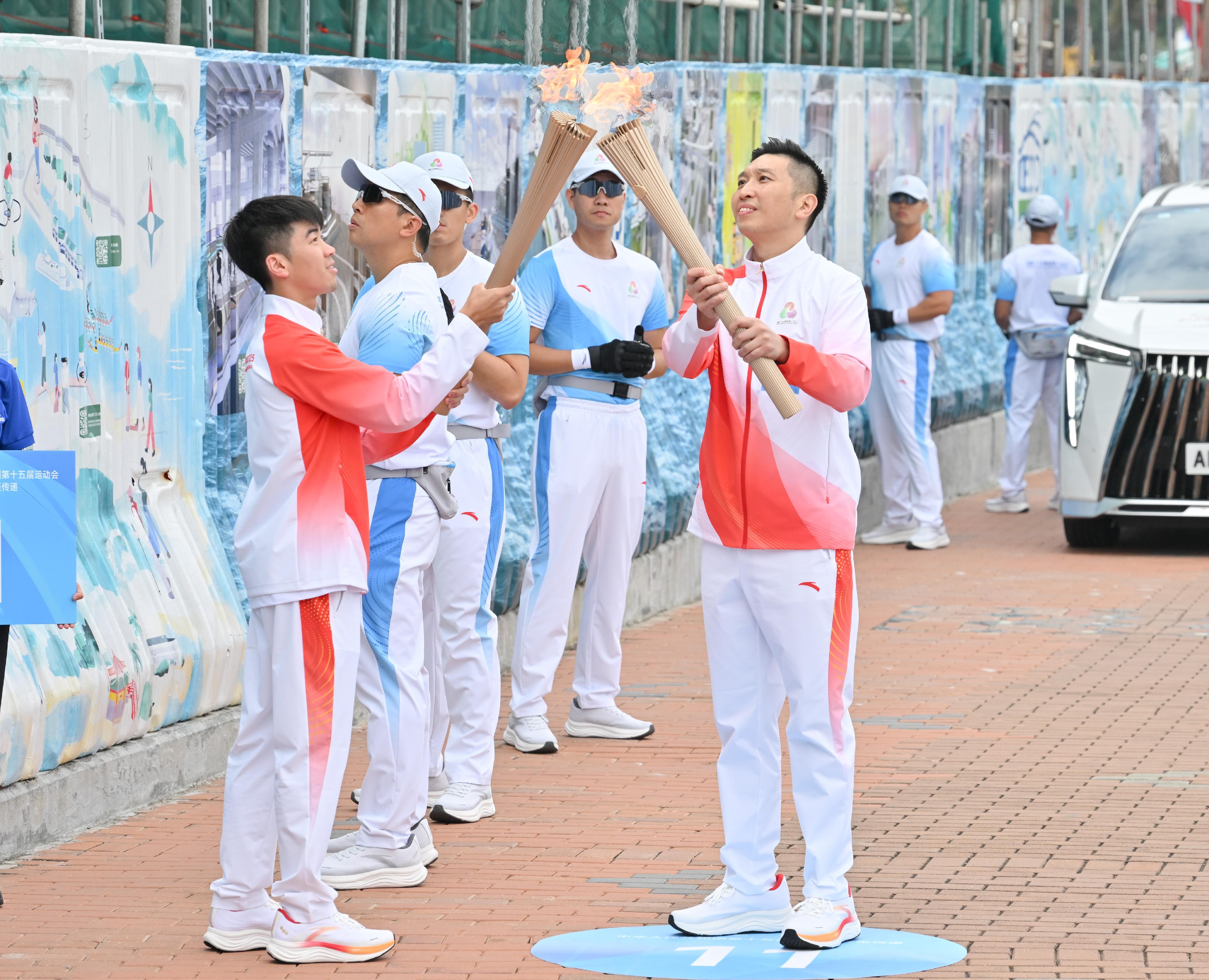 朱加勤（右）把火種傳給葉德朗（左）。