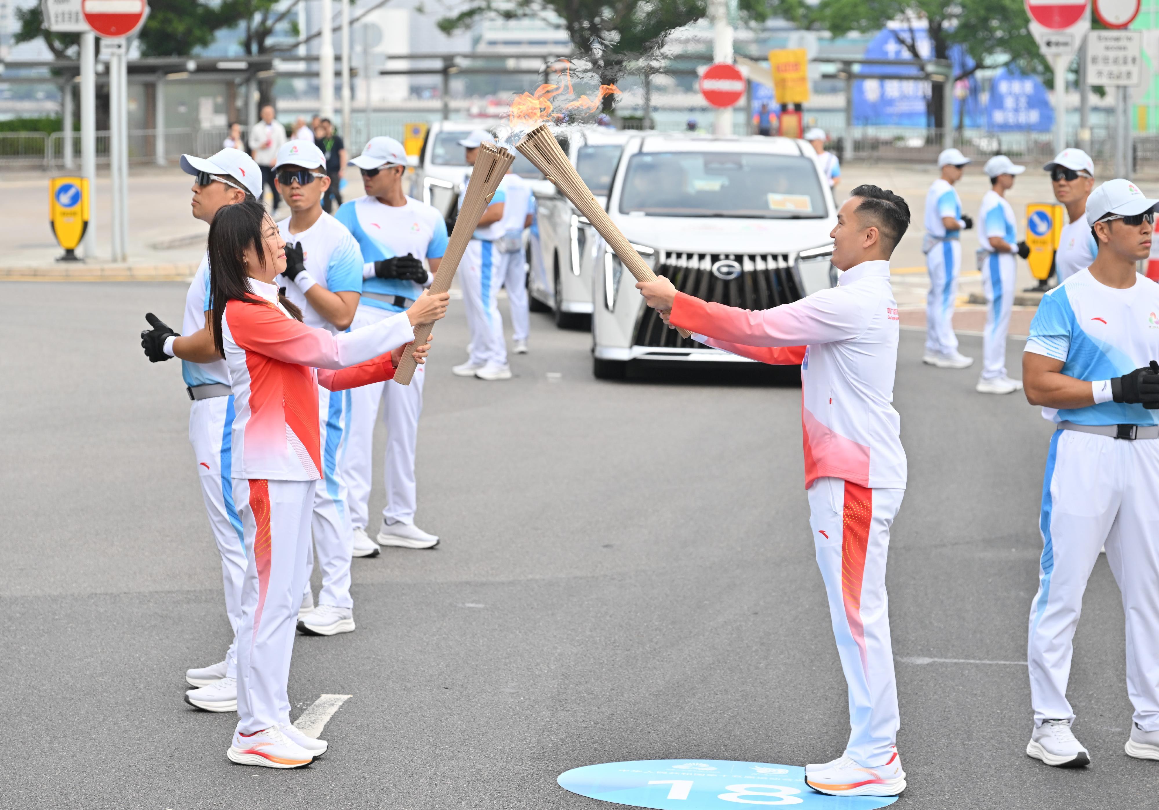 李振豪（右）把火種傳給王佩兒（左）。