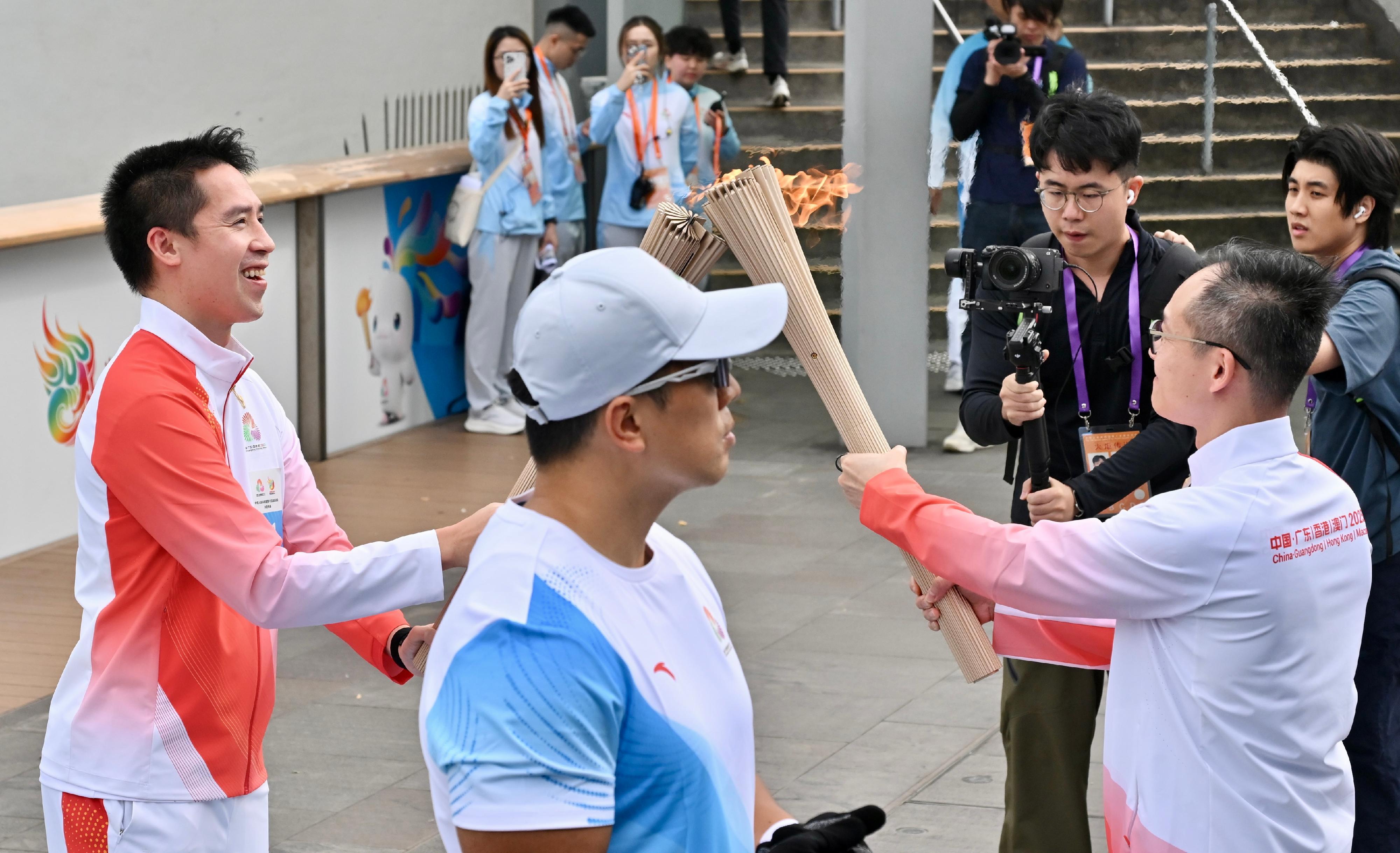 郭基煇（左）把火種傳給周潤宏（右）。