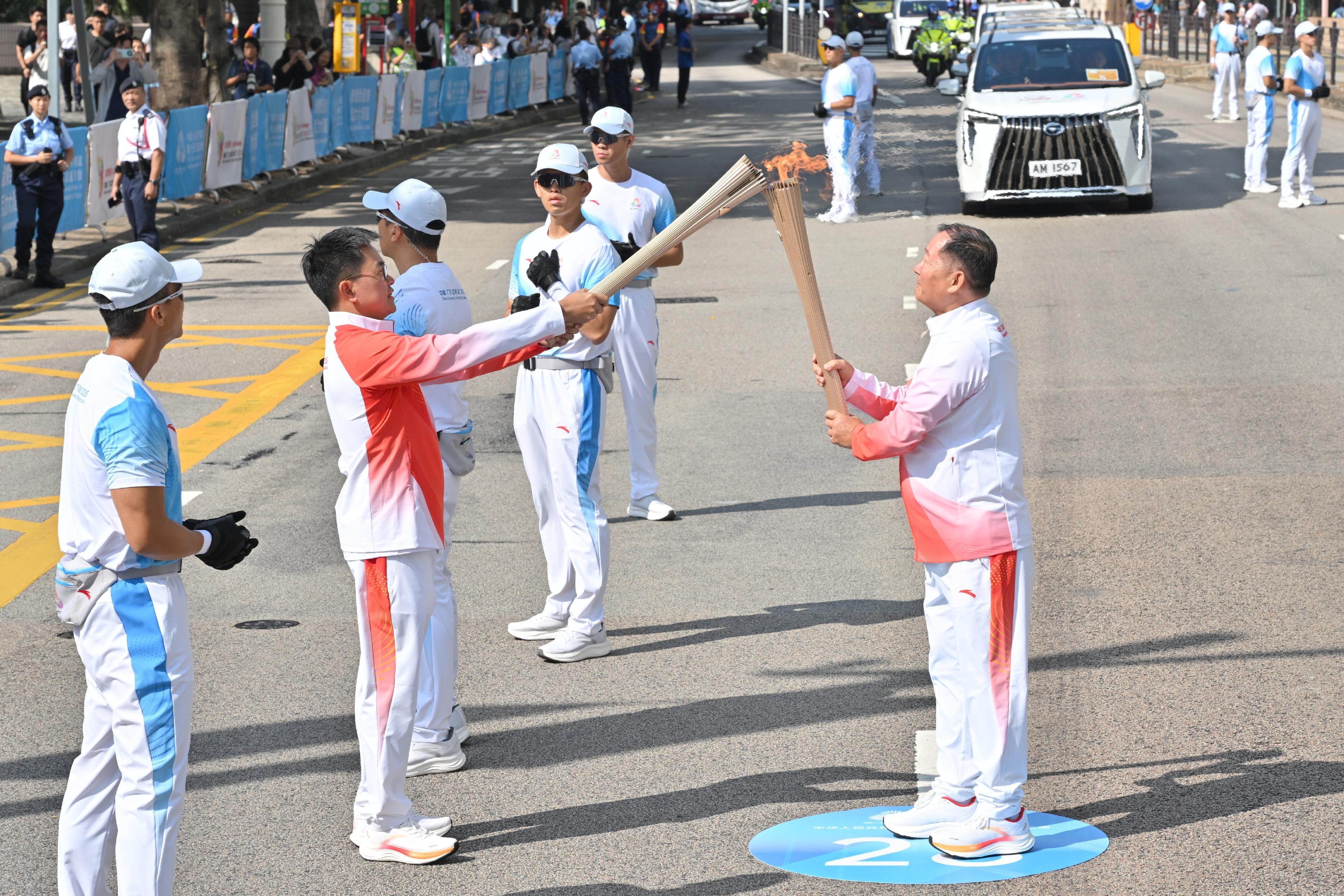 張偉良（右）把火種傳給林漢平（左）。